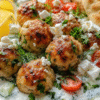 Juicy Greek chicken meatballs with fresh tzatziki sauce served on a white plate